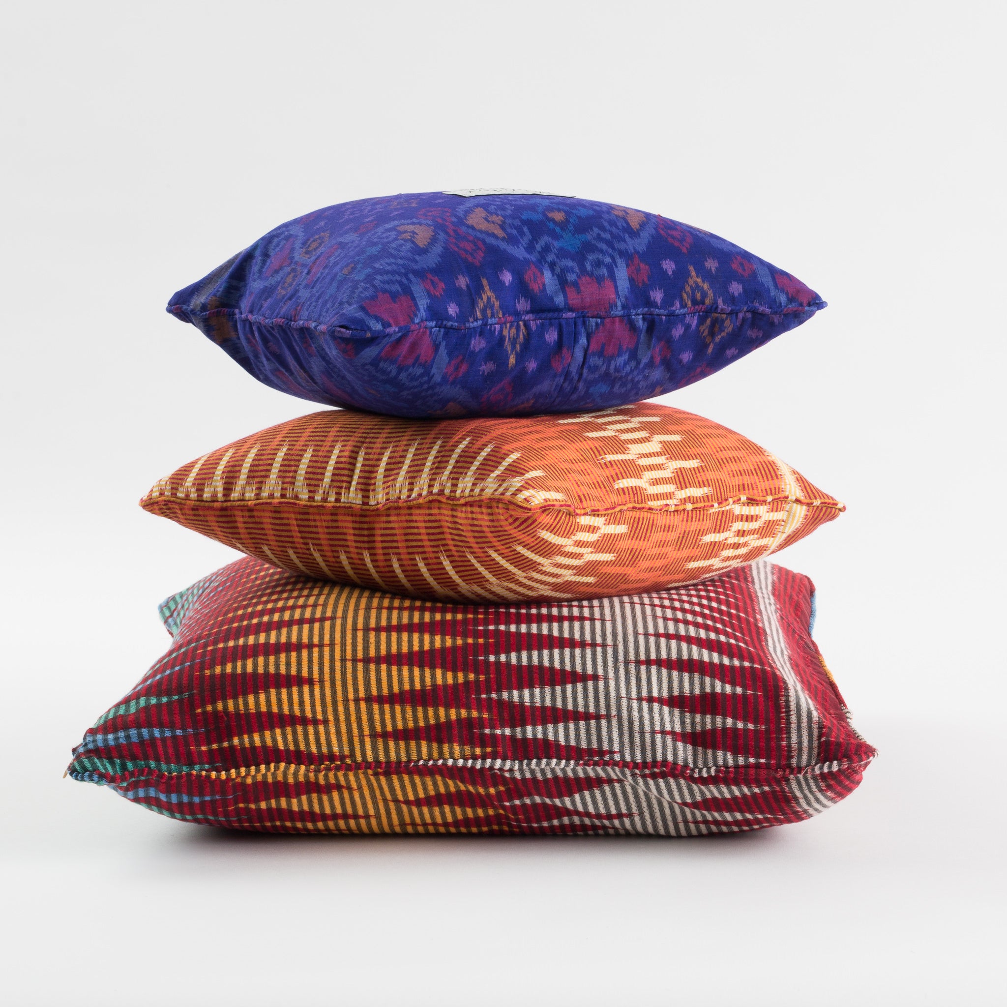 Three Stacked Ikat Cushions in Blue, Purple, Orange and Red colours